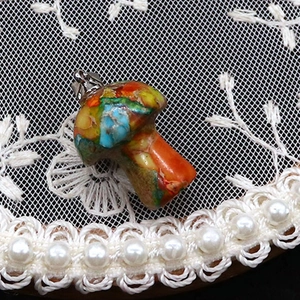 Dettaglio macro del ciondolo a fungo con mosaico in pietra colorata e gancio d'argento