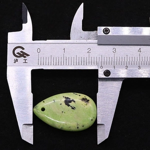 Nahaufnahme des hellgrünen Tropfensteinanhängers zeigt Breite von 2,6 cm mit Messschieber