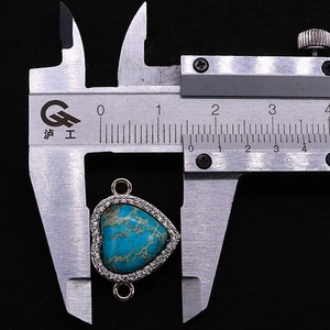 Vue macro d'un connecteur cœur en turquoise avec strass blancs et règle de mesure