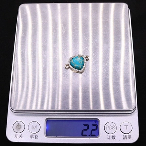 Vue détaillée du pendentif cœur en turquoise pesé sur une balance numérique
