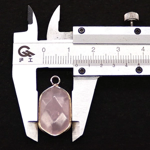 Detailopname van een 15 mm roze edelsteenhanger met vergulde rand en gefacetteerde snit