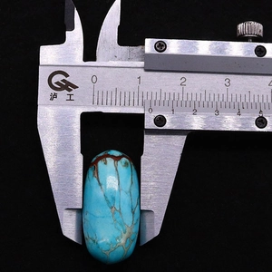 Macro view of measuring a 13mm turquoise oval stone bead with a digital caliper