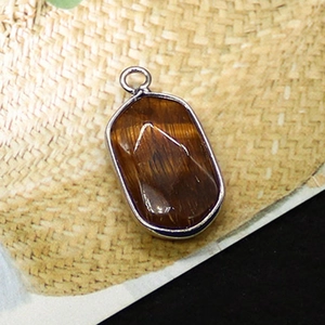 Macro shot of oval tiger eye pendant with silver plated edge and golden brown texture