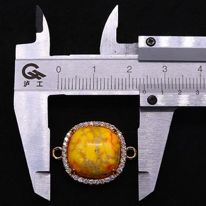 Makroaufnahme eines 22 mm gelben Kaiserstein-Anhängers mit Zirkonia-Rand auf Messschieber