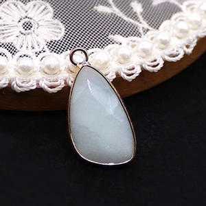 Detail view of water drop opal pendant with gold plated edges and lace decor