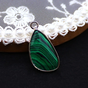 Close-up of teardrop malachite pendant with silver plating and green striped stone texture