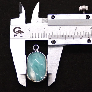 Detail shot showing a 13mm wide faceted natural amazonite pendant measured by a caliper