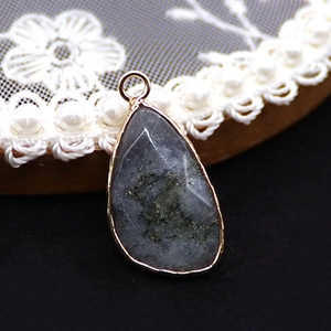 Macro detail of faceted teardrop labradorite stone pendant with elegant gold plated rim