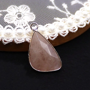 Detailed close-up of a faceted pink crystal pear-shaped pendant with silver metal edging