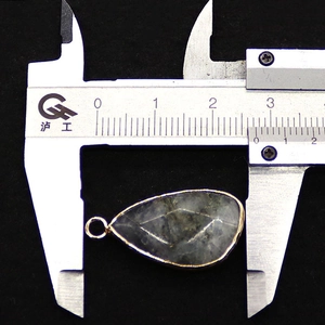 Macro shot of teardrop natural stone pendant with gold edge and caliper measurement