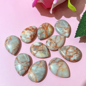 Polished teardrop-shaped agate beads with orange marble texture on pink background