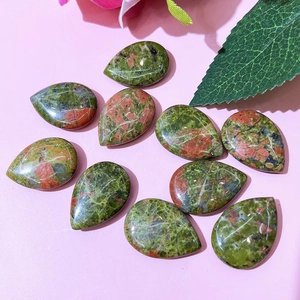 Flat lay of ten polished Unakite teardrop stones on a pink floral background