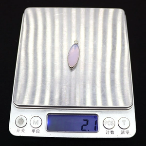 Detail shot of a marquise pink opal stone pendant being weighed on a digital scale