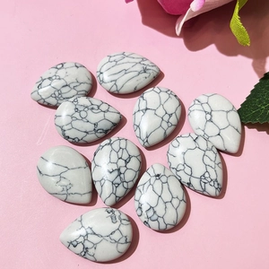 Flat lay of teardrop white turquoise beads with black veins on pink background