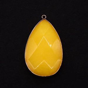 Macro detail of teardrop-shaped yellow stone pendant with gold plated bezel and faceted cut