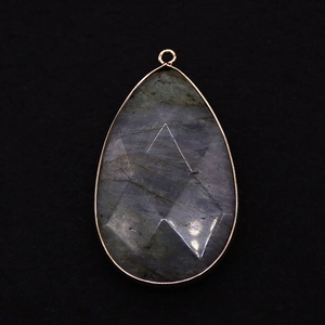 Macro detail of faceted teardrop labradorite pendant with golden electroplated edging