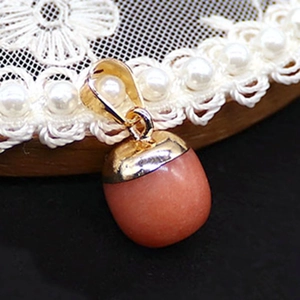 Makro-Detail des eichelförmigen rosa Quarz-Anhängers mit polierter Gold-Metallkappe