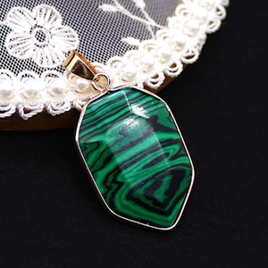 Detailed view of faceted malachite stone shield pendant with gold plated edges on black lace