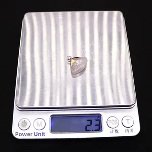 Vue macro d'un pendentif en quartz rose en forme d'éventail pesant 2,3 g sur balance