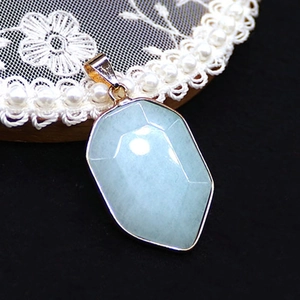 Macro detail of faceted light green stone pendant with gold-plated trim on lace display