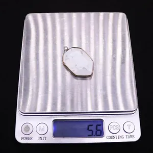 Macro view of white turquoise shield pendant with gold plating on a digital scale