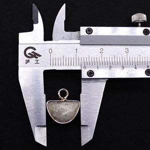 Macro view of D-shaped natural stone pendant showing a 13mm width measurement with a caliper
