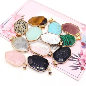 Shield-shaped natural stone pendants with gold plated edges on a floral card background