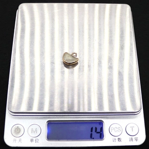 Detailed photo showing a 1.4g weight measurement of a gold moon stone pendant on a scale
