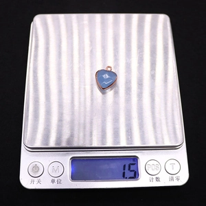 Gros plan d'un pendentif cœur bleu en pierre sur une balance pesant 1,5 gramme