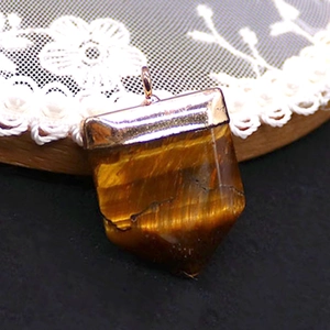 Macro shot of tiger eye stone pendant with rose gold plating on a lace background