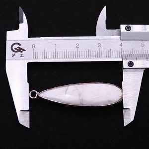Detail showing natural white turquoise teardrop pendant size measurement with a caliper