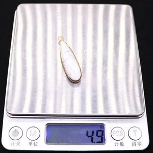 Weight measurement of white natural stone teardrop pendant with gold-plated edge at 4.9g