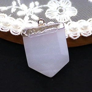 Macro view of light purple stone pendant with gold metal clasp on black lace background