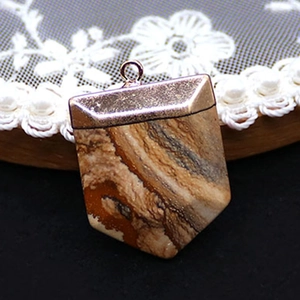 Macro detail of sword-shaped natural stone pendant with vintage bronze metal frame