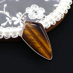 Macro detail of a shield-shaped tiger eye stone pendant with polished metallic edge