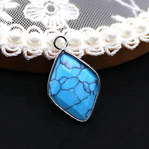 Detailed close-up of a blue natural stone rhombus pendant with a vintage silver metal frame