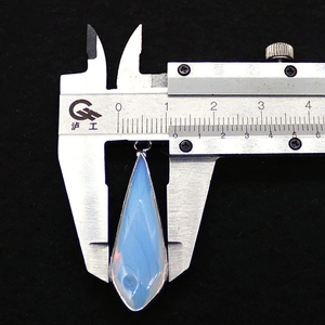Macro view measuring a 14mm teardrop stone pendant with silver edging using a caliper