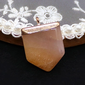 Macro shot of geometric orange aventurine stone pendant with rose gold metal edging and bail