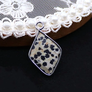 Macro view of a rhombic Dalmatian Jasper stone pendant with silver metal edge and hanging ring