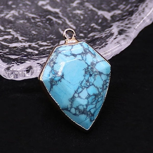 Macro shot of turquoise stone pendant with gold plated rim and black spiderweb texture