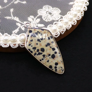 Macro detail of natural spotted stone pendant with elegant gold plated metal edge
