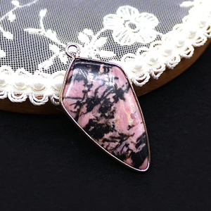 Detail view of pink spotted stone shield pendant with silver metal edging on lace