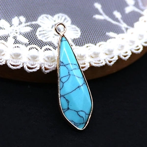 Gedetailleerde weergave van een druppelvormige turquoise hanger met gouden metalen rand