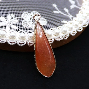 Macro-opname van druppelvormige natuursteen hanger met gouden plating voor sieraden