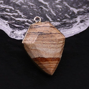 Macro detail of shield-shaped jasper pendant with natural brown layers and gold plated edges