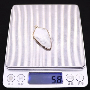 Détail du pendentif en pierre en forme de bouclier pesant 5,8 g sur une balance