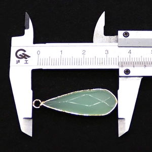 Detailopname van groene druppelvormige hanger met gouden rand en 3,5 cm afmeting op fluweel
