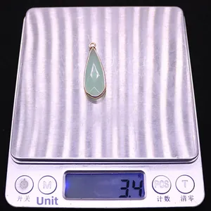 Macro d'un pendentif en pierre naturelle en forme de goutte pesant 3,4 g sur une balance