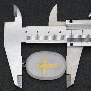 Mesure de la largeur du pendentif croix en pierre blanche avec un pied à coulisse