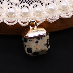 Macro shot of square Dalmatian jasper stone pendant with gold-plated metal cap details
